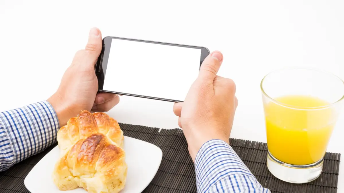 Ilustrasi seseorang menggunakan ponsel saat makan. Perhatian yang terbagi antara layar dan makanan dapat membuat proses makan menjadi kurang diperhatikan. Foto: freepik