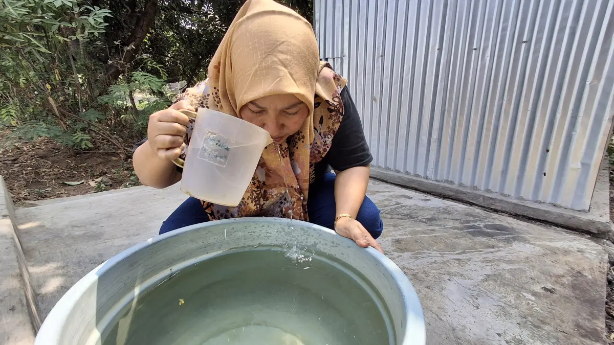 Warga tunjukkan air yang berbau karena diduga tercemar. (Foto Asad MS)