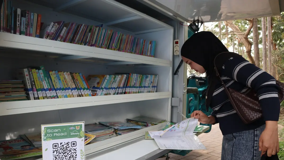 Pengunjung melihat koleksi buku di perpustakaan keliling yang terparkir di Taman Brantas Kota Kediri. (Foto: Ayu Isma)