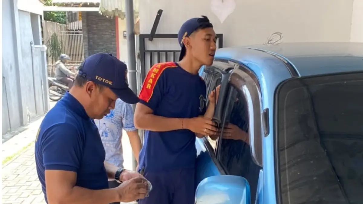 Petugas damkar saat sedang berusaha melakukan evakuasi anak yang terjebak di mobil. (foto Damkar Kabupaten Kediri)