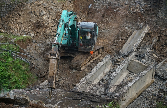 DIKEBUT: Pekerjaan proyek jembatan Ngadi-Jeli, Kecamatan Mojo menggunakan dua alat berat. Itu untuk membongkar bangunan lama yang tiang pancangnya masih menancap di tanah. (Wahyu Adji/JPRK)
