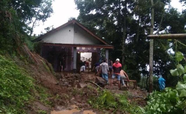 AKIBAT BENCANA: Warga bergotong-royong membersihkan sisa tanah longsor di rumah warga Desa Jugo, Kecamatan Mojo kemarin. (BASUKI FOR JPRK)
