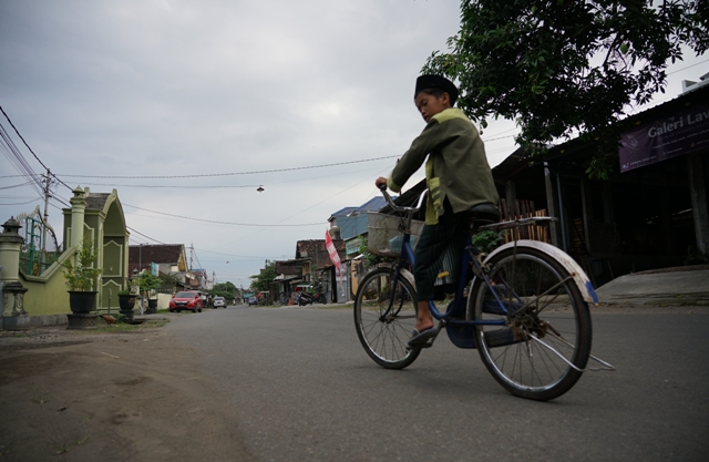 MAKIN LUAS: Seorang bocah bersepeda di jalan Desa Jongbiru, Kecamatan Gampengrejo yang sebagian lahan milik warganya dibebaskan untuk proyek pelebaran jalan akses ke jembatan. (Wahyu Adji/JPRK)