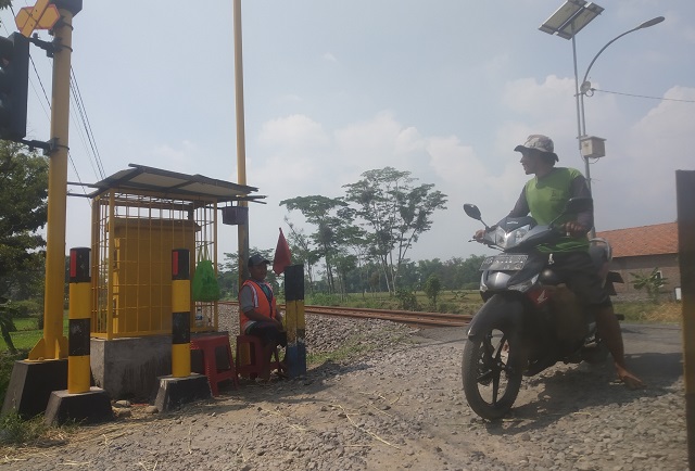 CEGAH CELAKA: Fikri sedang menjaga rel perlintasan kereta api yang bersimpangan dengan jalan desa di Dusun Gempol, Kecamatan Kayenkidul. (Aden/JPRK)