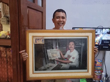 KENANGAN TAK TERLUPA: Santoso menunjukkan fotonya membawa koran Jawa Pos Radar Kediri yang dibingkai pigura di tokonya, Jalan Ahmad Yani, Kelurahan Ngadirejo, Kecamatan Kota Kediri. (Foto: Habibah A. Muktiara)
