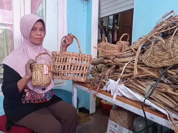 TANGAN KREATIF: Praptina menganyam batang eceng gondok kering dijadikan kerajinan yang bernilai jual, di rumahnya (30/6). (Foto: Rekian)