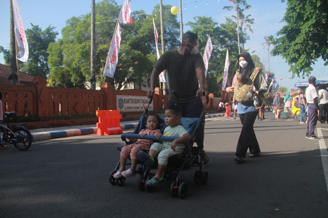 CFD PERTAMA SETELAH PANDEMI: Pengunjung Car Free Day (CFD) mengajak buah hatinya jalan-jalan di sekitar Alun-Alun Nganjuk. Masyarakat antusias mengikuti CFD di hari Minggu. (Foto: Andhika Attar)