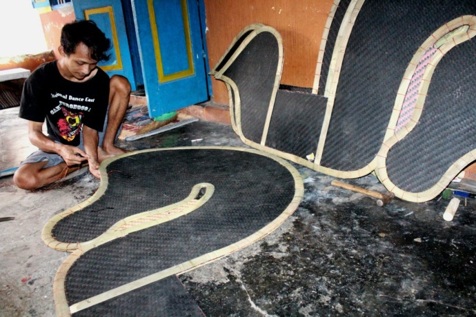 SEPENUH HATI: Wahyudi Romadoni menjahit kuda lumping di rumahnya. Karyanya dijual hingga ke berbagai daerah di luar Jawa. (Foto: Iqbal Syahroni)