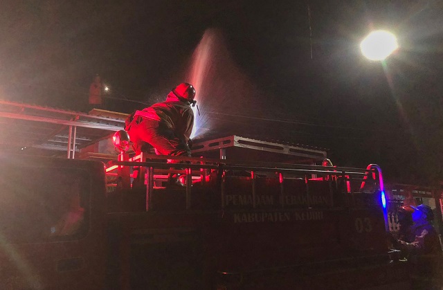 MELAWAN API: Petugas Pemadam Kebakaran Kabupaten Kediri melakukan pembasahan di garasi rumah warga yang terbakar. (POLSEK RINGINREJO FOR JPRK)