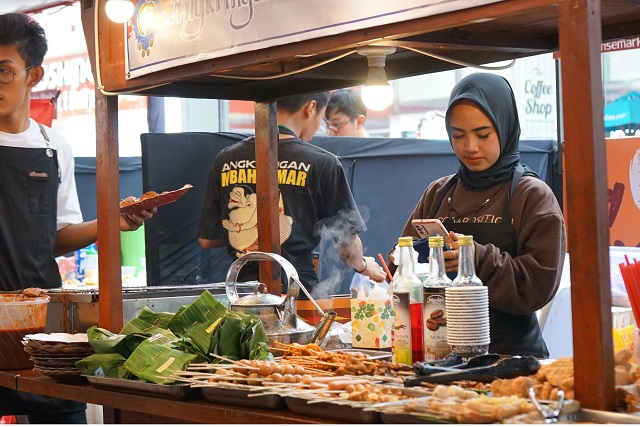 TAWARKAN ANEKA RASA: Seorang pedagang menerima pesanan hidangan dari konsumen yang mengunjungi lapaknya di acara bazar makanan bertajuk Kuliner Explorasa Street Food Festival. (Habibah A. Muktiara/JPRK)