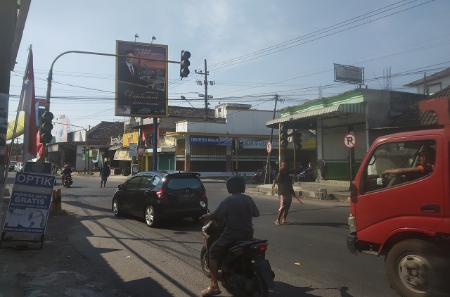ANTISIPASI: Seorang warga sukarela mengatur arus lalu lintas di perempatan Jalan Raya Sambi, Kecamatan Ringinrejo karena traffic light mati (1/8). (Khalqinus Taaddin/JPRK)