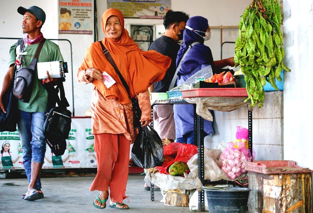 TENTENG: Seorang wanita membawa belanjaan yang ditempatkan dalam tas kresek ketika berbelanja di Pasar Setonobetek, Kota Kediri. (Foto: Wahyu Adji)