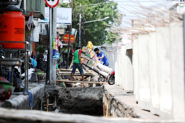 LEBIH LEBAR: Pekerja memperbaiki saluran drainase di Jl Pattimura yang setiap musim hujan selalu jadi daerah langganan banjir. (Foto: Wahyu Adji)