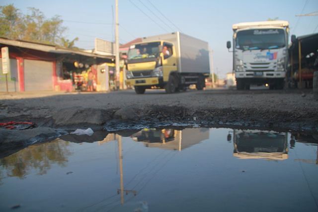 RUSAK PARAH: Lubang menganga di Jalan Raya  Guyangan. Sopir truk dan warga waswas saat melintas. (Foto: Andhika Attar)
