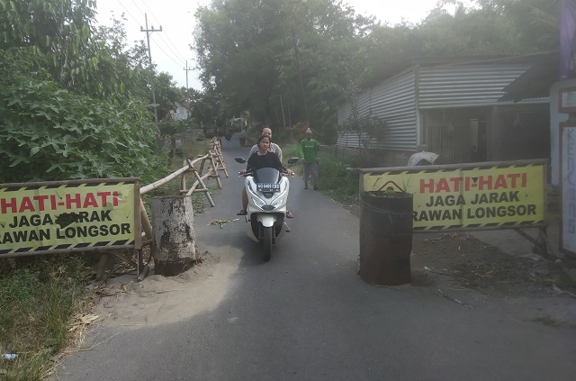 BUTUH PERHATIAN: Warga memasang pagar pembatas di pinggir jembatan penghubung tiga kecamatan yang plengsengannya amblas di Dusun Sidodadi, Desa Canggu, Kecamatan Badas. (Khalqinus Taaddin/JPRK)