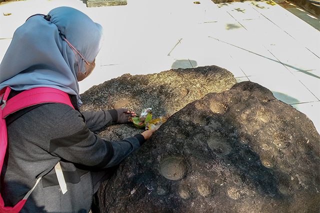 BESAR: Warga berada di dekat palinggih yang oleh warga disebut dengan batu dakon. (Foto: Rekian)