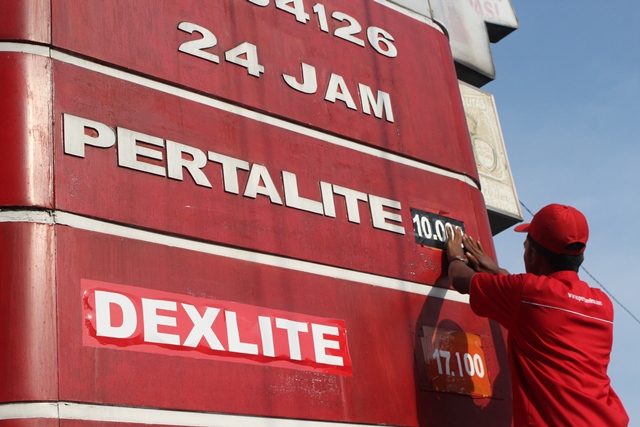 STOK KOSONG: Petugas SPBU Desa Sukorejo, Ngasem mengganti harga di papan SPBU kemarin sore. Di saat bersamaan, pertalite di sana dinyatakan kosong. (Foto: Iqbal Syahroni)