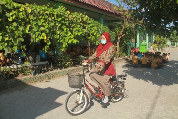 TAK BINGUNG BBM NAIK: Sumarni naik sepeda listrik saat berangkat mengajar di SDN 5 Joho kemarin. (Foto: Andhika Attar)