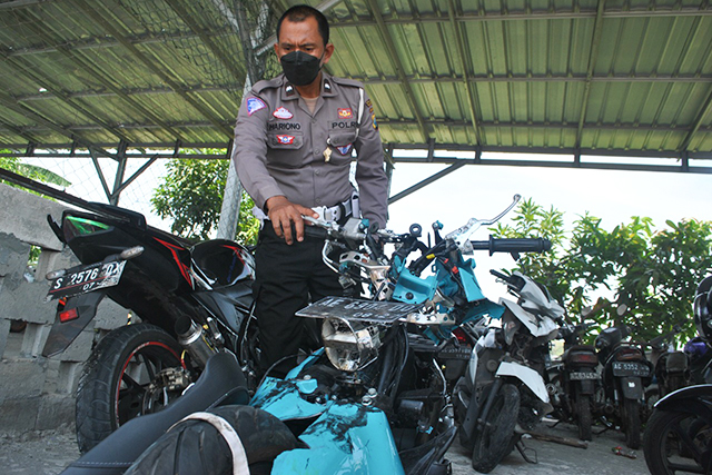 TAK BERBENTUK: Petugas Satlantas Polres Nganjuk menunjukkan sepeda motor Yamaha Fazzio yang tertabrak bus. (Foto: Karen Wibi)
