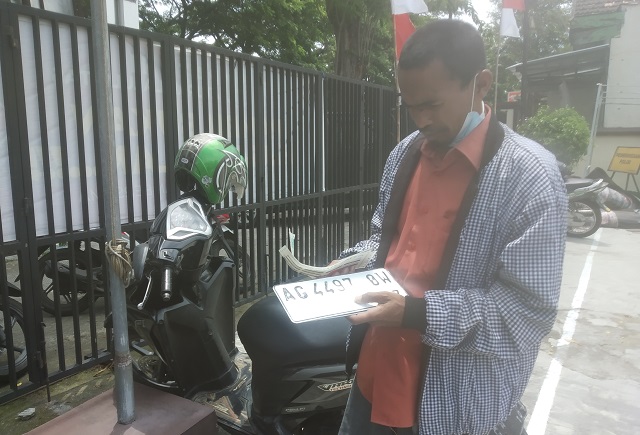 GANTI PUTIH: Saipul, warga Desa Wonokerto, Kecamatan Pelemahan menunjukkan plat nopol putih yang sudah mulai berlaku di Samsat I Kediri kemarin (13/10). (Khalqinus Taaddin/JPRK)