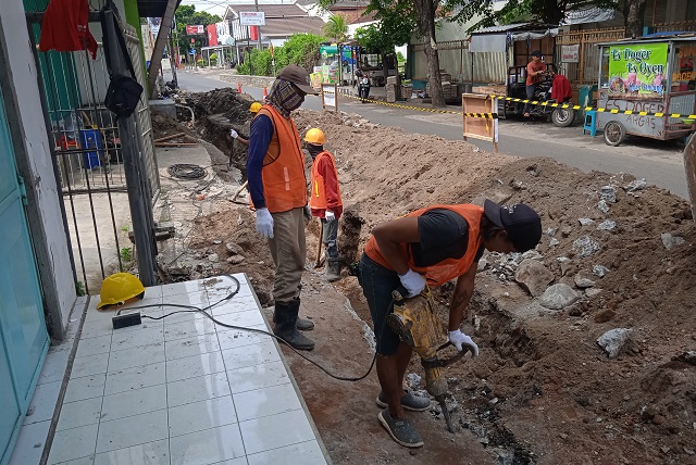 TAMBAH DALAM: Pekerja mengebor tanah dalam pengerjaan proyek pelebaran dan pengerukan saluran air di Jalan Tembus Kaliombo, Kota Kediri. (Fildatul Halwa/JPRK)