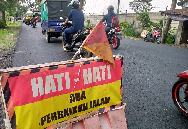 AKSES PADAT: Papan pemberitahuan dipasang di area proyek perbaikan jalan di jalur arah Purwoasri hingga Gampengrejo. (Rekian/JPRK)