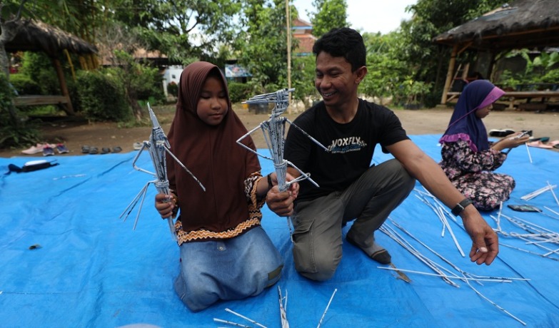 PANUTAN: Seorang ayah membantu putrinya membuat wayang dari koran bekas di Sekolah Alam Ramadhani, Mojoroto, Kota Kediri, kemarin (12/11). (Foto: Wahyu Adji Febrianto)