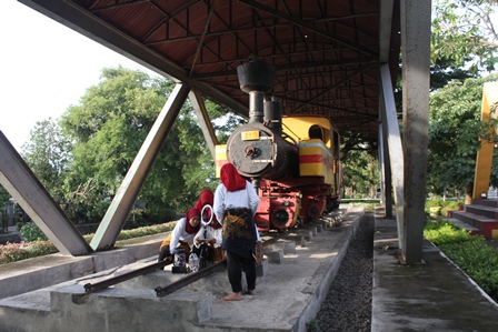BIKIN KONTEN: Sekelompok remaja berada di dekat lokomotif kuno yang dipajang di Taman Kepala Kereta. Sementara, seorang bocah tengah mengutak- atik tungku yang ada di bagian dalam lokomotif (foto insert). (Foto: Habibah A Muktiara)