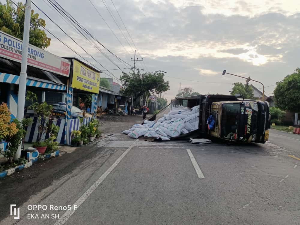 KECELAKAAN: Truk bermuatan pakan ternak terguling di pertigaan Barong, Kecamatan Tanjunganom kemarin. Sopir mengalami luka-luka. (Foto: Karen Wibi)