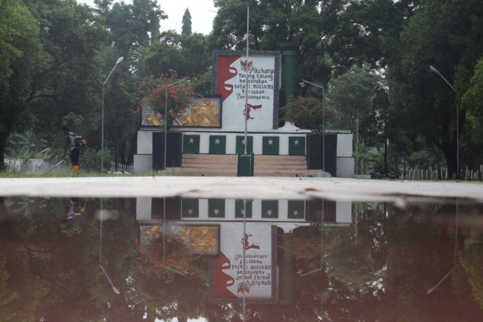 SAMBUT HARI PAHLAWAN: Khoirul membersihkan rumput di TMP Yudha Pralaya Nganjuk kemarin. Honor THL di bawah UMK Kabupaten Nganjuk. (Foto: Karen Wibi)