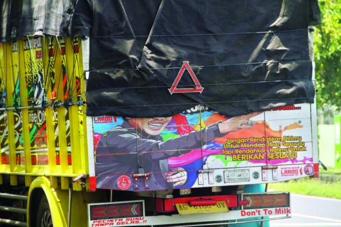 MENARIK PERHATIAN: Tulisan dan gambar di bak truk yang melintas di wilayah Nganjuk berisi tentang kata-kata bijak, kritik, dan guyonan. Banyak warga menjadikan tulisan dan gambar di bak truk sebagai status WA. (Foto: Andhika Attar)