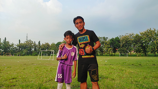 HARAPAN KELUARGA: M. Taufiq saat me- ngantar anaknya, Desta, latihan sepak bola di Lapangan Bangsal,Kecamatan Pesantren. (Foto: Iqbal Syahroni)