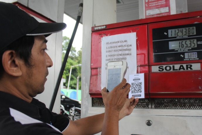 UJI COBA: Petugas SPBU Putih Gampengrejo melakukan scanning barcode QR yang baru didaftarkan sebelum dibawa oleh pengendara. (Foto: Rekian)
