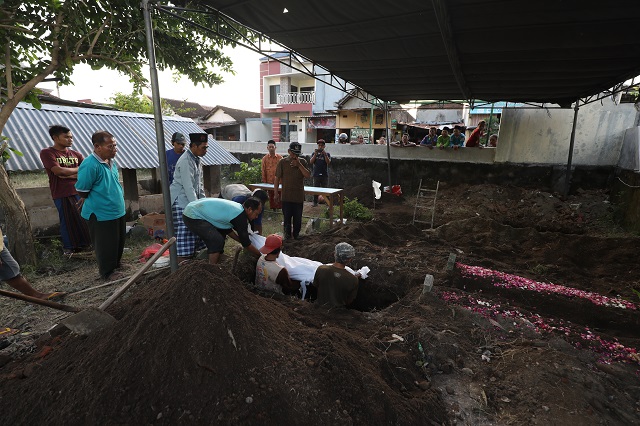 JADI PERHATIAN: Warga Desa Jongbiru menyaksikan pembongkaran makam warga yang terdampak proyek pelebaran jalan akses untuk Jembatan Mrican kemarin. (Foto: Wahyu Adji)