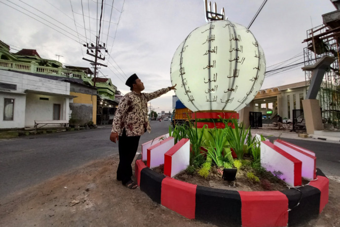 WAJIB 99 NAMA: Warga mengecek nama-nama Allah di Tugu Asmaul Husna, Kelurahan Warujayeng kemarin. (Foto: Andhika Attar)