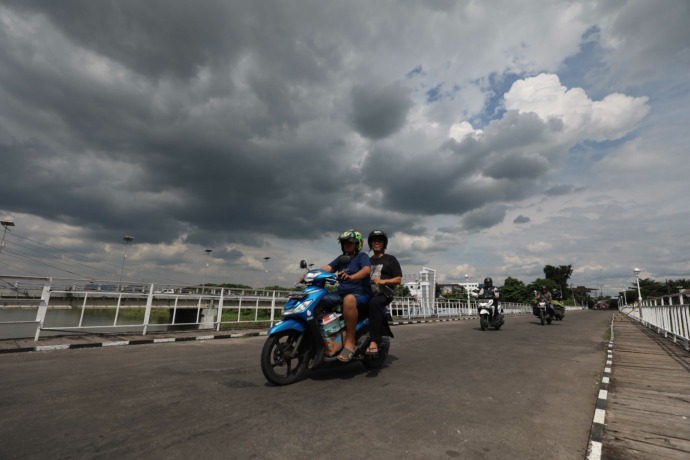 AWAN PEKAT: Warga melintas di Jembatan Lama Kota Kediri ketika mendung gelap menggelayut di langit. Sesuai peringatan BMKG dalam beberapa hari mendatang cuaca ekstrem masih terjadi dengan potensi terjadi hujan dengan intensitas tinggi.