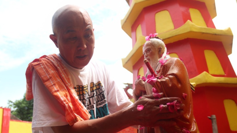 TAHUN KELINCI AIR: Sebastian memandikan patung dewa. Sembahyang Cie Suak untuk buang sial (Foto: Karen Wibi)