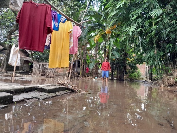 TERSUMBAT SAMPAH: Warga Dusun Jegles, Desa Tarokan, Kecamatan Tarokan beraktivitas di permukimannya yang masih terendam banjir kemarin. (Foto: Emil)