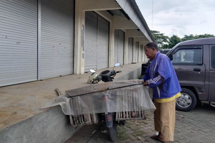 NGANGGUR: Seorang pedagang memarkir motornya di depan kios mangkrak di Pasar Induk. (Foto: Emilia Susanti)
