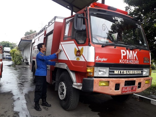 BERSIAP: Petugas PMK hendak menaiki kendaraan pemadam kebakaran (damkar) yang terparkir di halaman depan kantor PMK Kota Kediri kemarin. (Foto: Ayu)