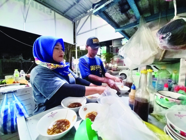 JAGA KUALITAS RASA: Gunawi (kanan) dan rekannya menyiapkan pesanan pelanggan di warung mi ayam Srikandi kemarin malam. Warung mi ayam di Kertosono ini telah berdiri sejak tahun 1992. (Foto: Andhika Attar)