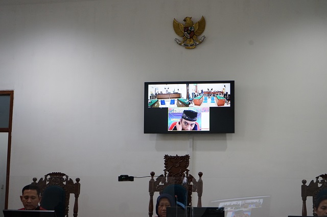 MASIH PIKIR-PIKIR: Terdakwa Arif Pradita mengikuti persidangan telekonferensi di layar monitor PN Kota Kediri. ( Foto: Habibah Anisa Muktiara )