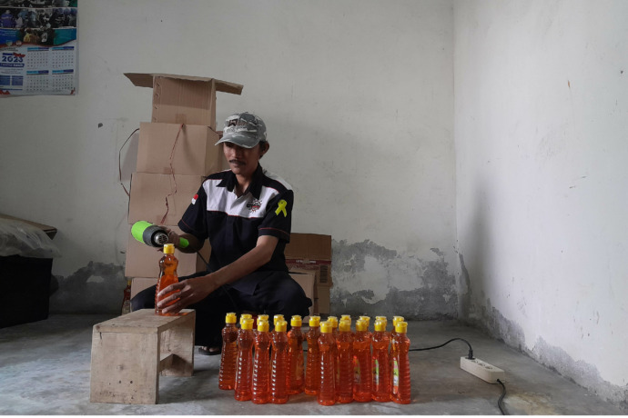 PENGEPAKAN: Ansori melakukan proses pengepresan tutup kemasan sabun cuci piring yang menjadi produknya kemarin. (  Foto: Emilia Susanti )