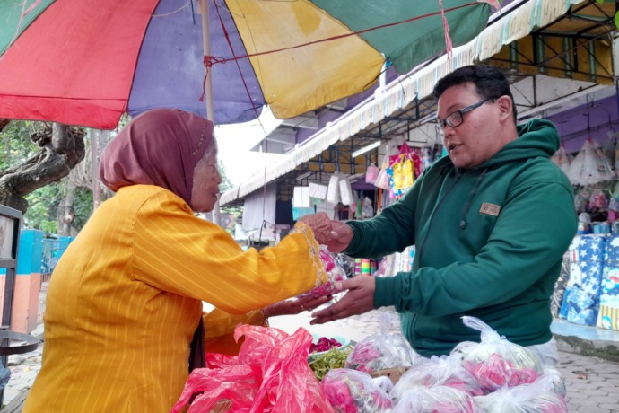 TRANSAKSI: Matiah melayani pembeli bunga tabur di lapaknya, Pasar Bandar, Mojoroto, Kota Kediri. (Foto: Emilia Susanti)