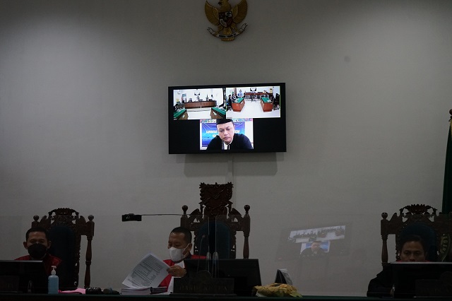 MENYESAL: Bagus Setiawan mengikuti persidangan secara online di layar monitor ruang Pengadilan Negeri Kota Kediri, kemarin. (Foto: Habibah A. Muktiara)