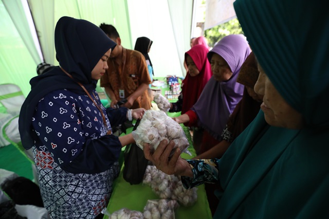 TEKAN INFLASI: Petugas DKPP Kabupaten Kediri melayani masyarakat yang berminat membeli bahan kebutuhan pokok dalam pasar murah yang digelar di Balai Desa Bulusari, Tarokan. (Foto: Wahyu Adji)