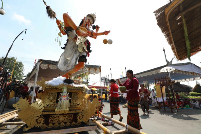 PATUNG RAKSASA: Seorang umat Hindu memercikkan air suci ke ogoh-ogoh berupa raksasa bertangan empat sebelum diarak, di Bundaran Sekartaji, Kota Kediri kemarin. (Foto: Wahyu Adji)