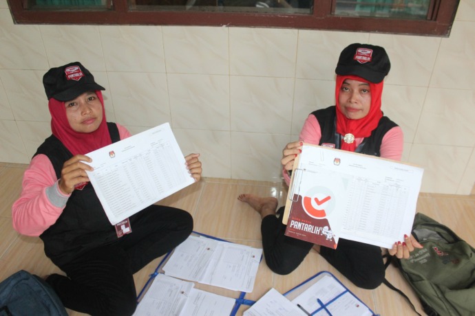 ISTIRAHAT: Ita Rusita (kanan) dan Sriamu menunjukkan data pemilih ketika berada di Sekretariat PPS Desa Kalibelo, Kecamatan Gampengrejo. (Foto: Rekian)