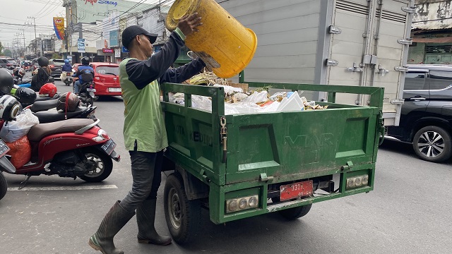 TIDAK LIBUR: Petugas kebersihan DLHKP mengangkut sampah di Jalan Dhoho, Kota Kediri kemarin. (Foto: Melisa Mudawatul)