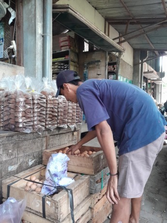 BELUM STABIL: Penjual telur menata dagangannya sambil menunggu konsumen di Pasar Induk Pare. (Foto: Emilia Susanti)